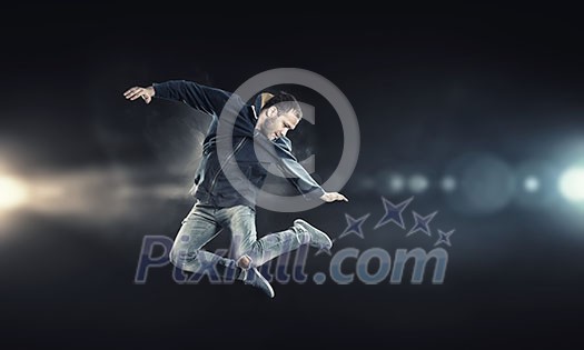 Modern style male dancer jumping in lights of spotlight Modern style male dancer jumping in lights of spotlight