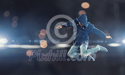 Modern style male dancer jumping in lights of spotlight