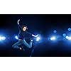 Young woman dancer jumping in spotlights on dark background