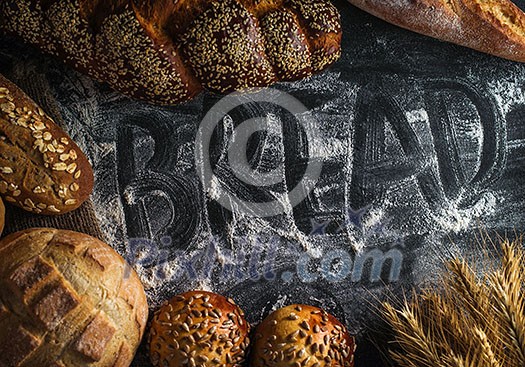 Background with fresh bread and inscription 'Bread' on flour. Background with fresh bread and inscription 'Bread' on flour.