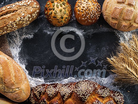 Assortment of fresh bread on the dark table. Copyspace for text.