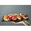 delicious variety of Italian bruschetta on a ceramic tray holds the hand of man