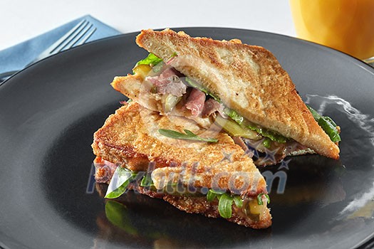Italian ciabatta sandwich with parma ham and herbs on black plate Italian ciabatta sandwich with parma ham and herbs on black plate