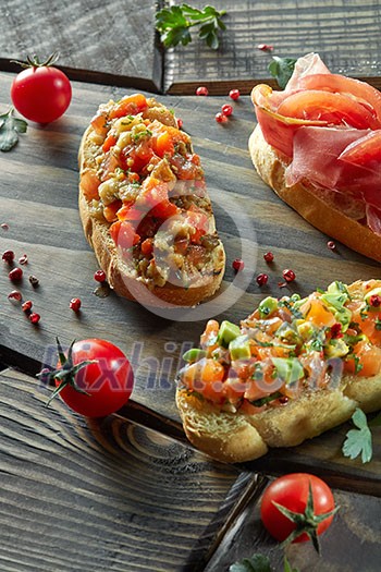 assorted Italian appetizer bruschetta on a dark wooden background