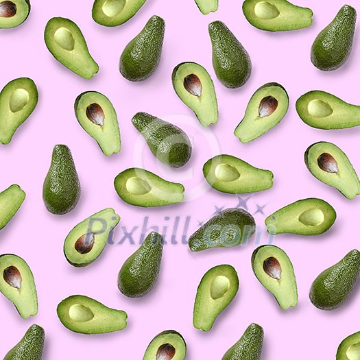 whole and halves of a green avocado on a pink background flat lay