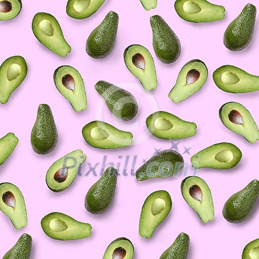 whole and halves of a green avocado on a pink background flat lay whole and halves of a green avocado on a pink background flat lay