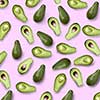 whole and halves of a green avocado on a pink background flat lay