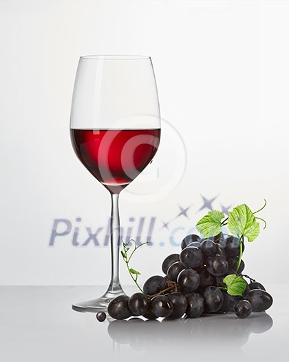 a bunch of blue vines and a glass of red wine on a white background