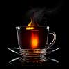 glass cup with tea and saucer isolated on black background close-up