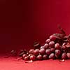 a bunch of ripe grapes and leaves of grapes isolated on a red background