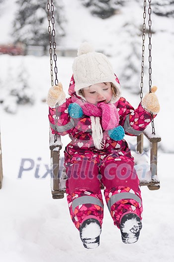 child outdoor in park at winter day with fresh snow, cute little girl swing and playing