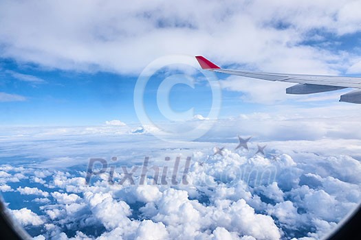 Wing aircraft in airplane window. View of the sky and clouds through the aircraft window.