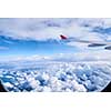 Wing aircraft in airplane window. View of the sky and clouds through the aircraft window.