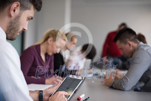 close up of  businessman hands  using tablet, people group in office meeting  room blurred in backgronud