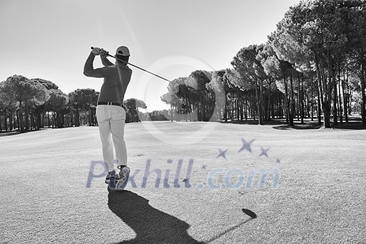 golf player hitting shot with club on course at beautiful morning with sun flare in background golf player hitting shot with club on course at beautiful morning with sun flare in background