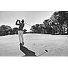 golf player hitting shot with club on course at beautiful morning with sun flare in background