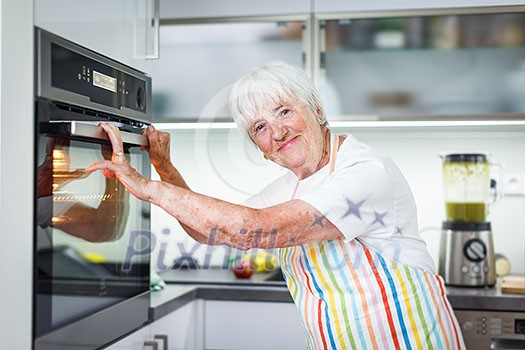 Senior woman cooking in the kitchen - eating and cooking healthy for her family; putting some potates in the oven, enjoying active retirement (shallow DOF; color toned image) Senior woman cooking in the kitchen - eating and cooking healthy for her family; putting some potates in the oven, enjoying active retirement (shallow DOF; color toned image)