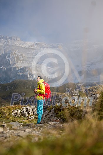 Pretty, young female hiker walking in high mountains (shallow DOF) Pretty, young female hiker walking in high mountains (shallow DOF)