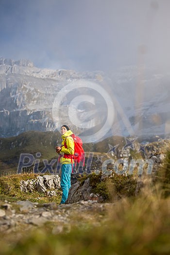 Pretty, young female hiker walking in high mountains (shallow DOF)