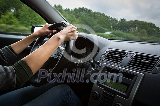 Male driver's hands driving a car on a highway (color toned image; shallow DOF)