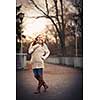 Autumn/winter portrait: young woman dressed in a warm woolen cardigan posing outside in a city park