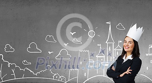 Young businesswoman in paper crown and sketches at background Young businesswoman in paper crown and sketches at background