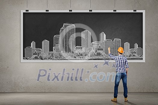 Rear view of man engineer in helmet drawing on chalkboard Rear view of man engineer in helmet drawing on chalkboard