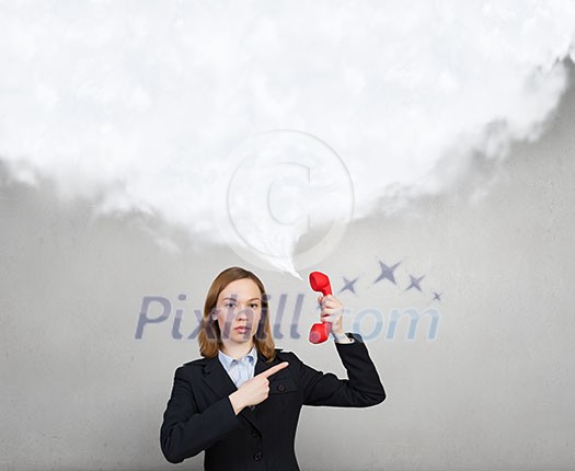 Portrait of young businesswoman with red phone receiver in hands