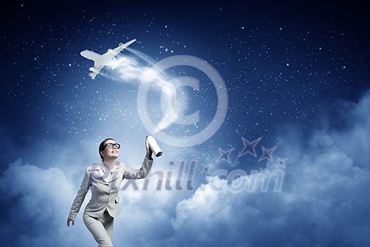 Young woman in suit and glasses spraying airplane in sky