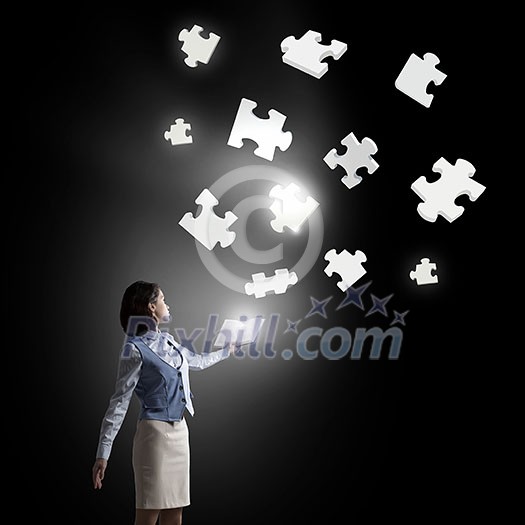 Businesswoman with book in hands and puzzle elements in air Businesswoman with book in hands and puzzle elements in air