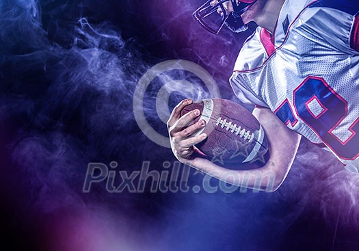 American football player holding ball while running on field at night