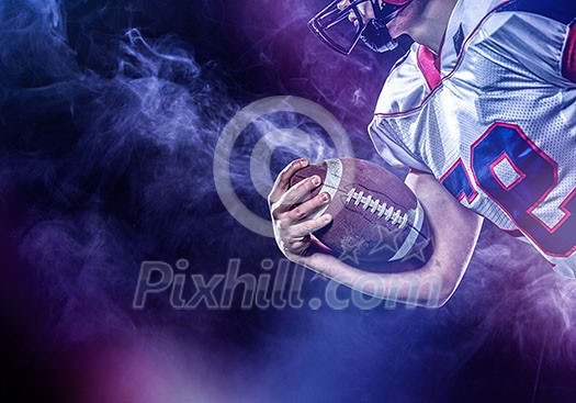 American football player holding ball while running on field at night American football player holding ball while running on field at night