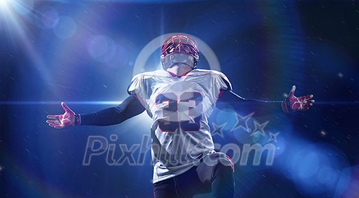 american football player celebrating after scoring a touchdown on the field of big modern stadium with lights and flares at night