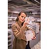 Pretty, young woman in a home supply store choosing the right glasses for her wine addiction (color toned image; shallow DOF)