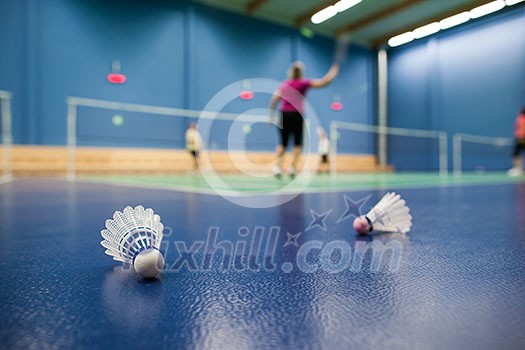 badminton - badminton courts with players competing; shuttlecocks in the foreground (shallow DOF; color toned image)