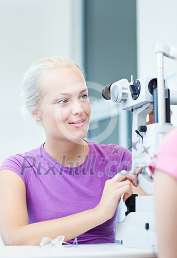 optometry concept - portrait of a young pretty optometrist using slit lamp, checking her patient's sight (color toned image) optometry concept - portrait of a young pretty optometrist using slit lamp, checking her patient's sight (color toned image)