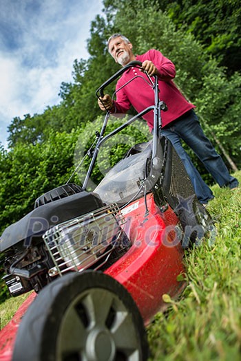 Senior man mowing the lawn in his garden Senior man mowing the lawn in his garden
