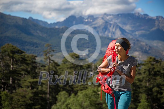 Pretty, female hiker in high mountains packing her backpack