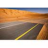 Modernity versus nature concept - end of civilisation, beginning of desert. Modern paved highway ending up in sand dunes.