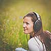 portrait of a pretty young woman listening to music on her mp3 player outdoors (daydreaming)