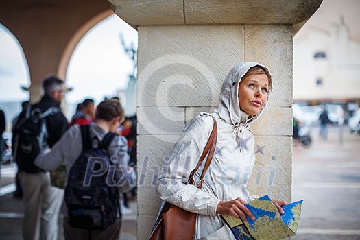 Gorgeous female tourist with a map discovering a foreign city - waiting for the rain to stop (shallow DOF; color toned image) Gorgeous female tourist with a map discovering a foreign city - waiting for the rain to stop (shallow DOF; color toned image)