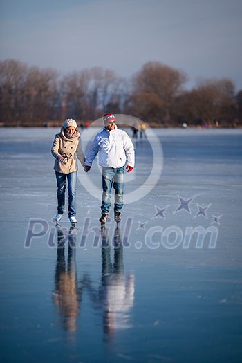 Couple ice skating outdoors on a pond on a lovely sunny winter day