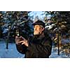 Handsome senior man shotting video with his adventura outdoor camera on a grip handle outdoors on a lovely winter day, enjoying retirement