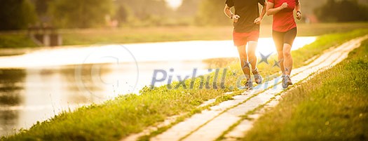 Couple running outdoors, at sunset, by a river, staying active and fit Couple running outdoors, at sunset, by a river, staying active and fit