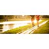 Couple running outdoors, at sunset, by a river, staying active and fit