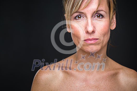 Portrait of a smiling middle aged caucasian woman against dark background - radiating confidence and feminity (shallow DOF; color toned image)