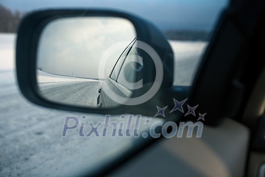 Rear view mirror of a modern car on a winter day(shallow DOF; color toned image)