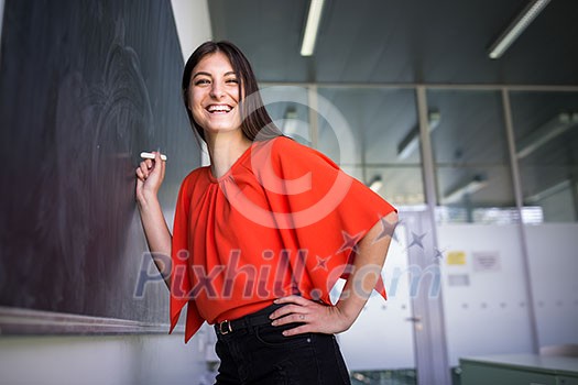 Pretty, young college student writing on the chalkboard/blackboard during a math class