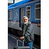 Handsome senior man taking a train, waiting for his family to pick him up (color toned image)