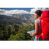 Pretty, female hiker in high mountains packing her backpack